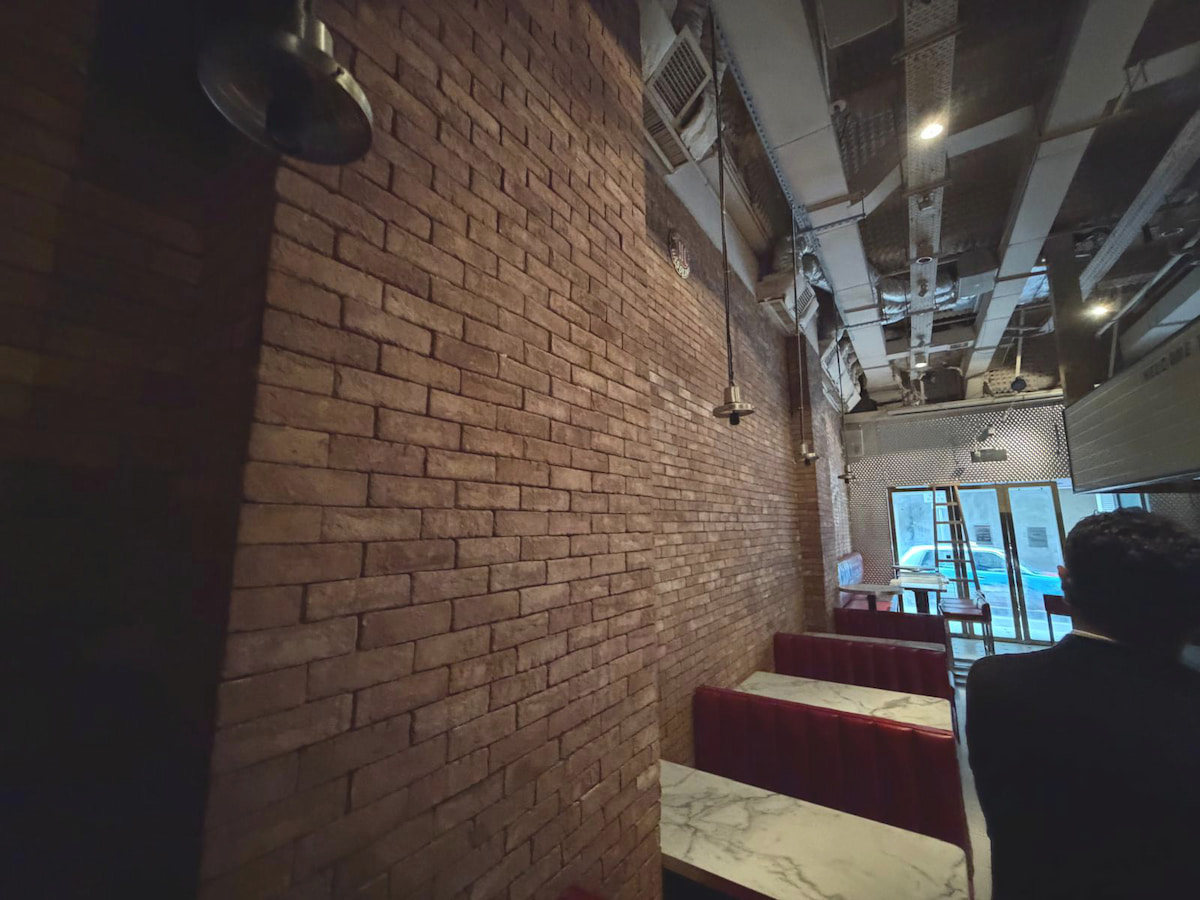 Brick-walled restaurant on Wyndham Street, Central, features red booths, marble tables, and dimly lit exposed ceiling pipes.