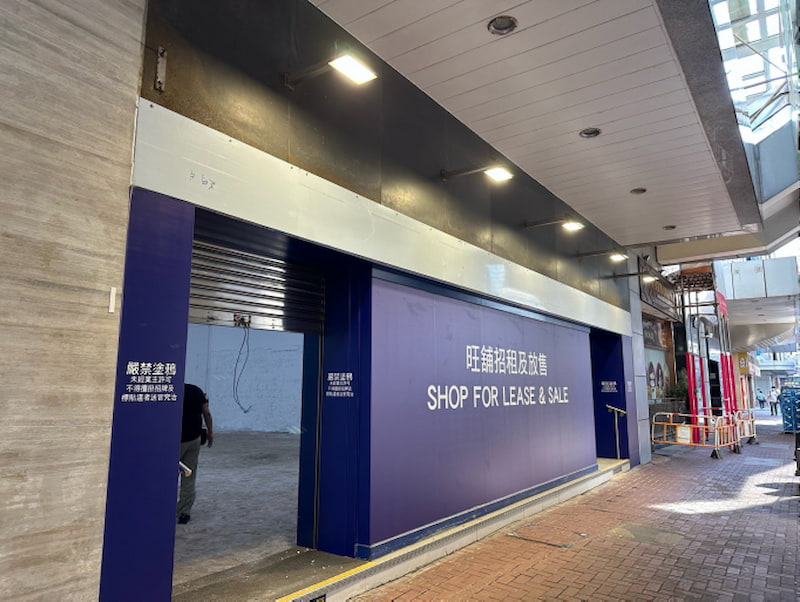 Shop on Connaught Road, Central. Empty, unfinished storefront Central with blue signage in English and Chinese.