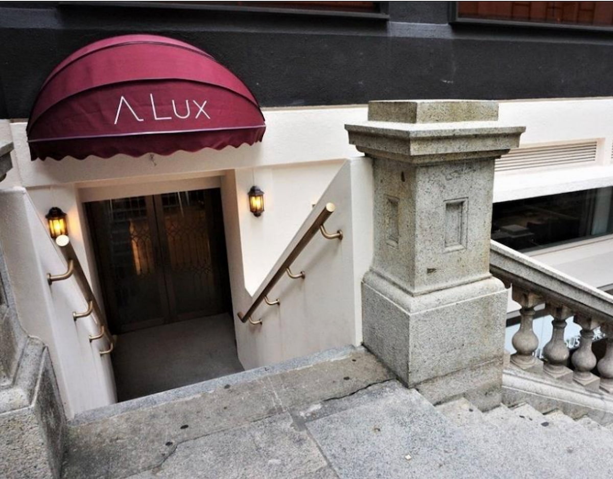 中環雪廠街一道紅色帳篷標示A Lux,覆蓋設有黃銅欄杆的樓梯,通往下層入口。