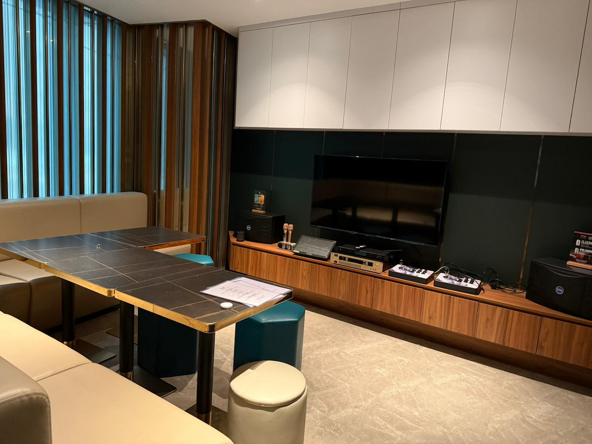 Room on Yip Kan Street with beige seating, a long table, television, audio equipment and wall cabinets.
