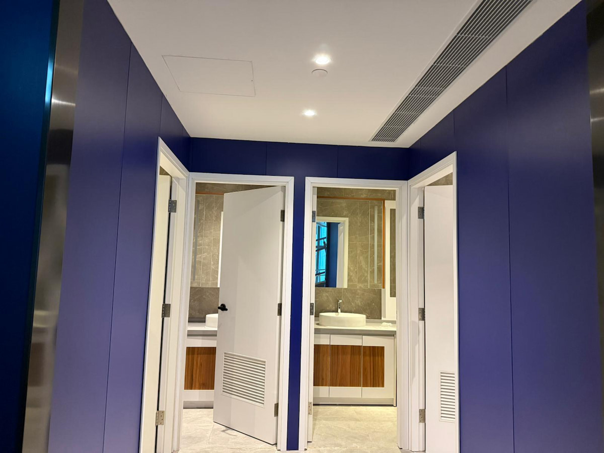 Two open white doors show bathrooms with sinks, mirrors, and blue walls on Yip Kan Street, Wong Chuk Hang.