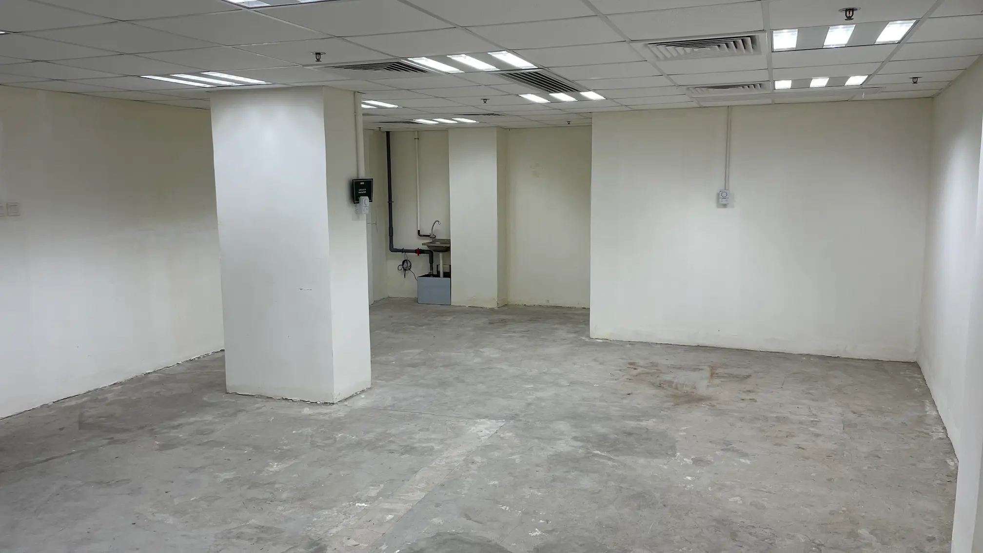 中環都爹利街一個空置房間，設有白牆、水泥地面、天花燈及一個工作水槽。