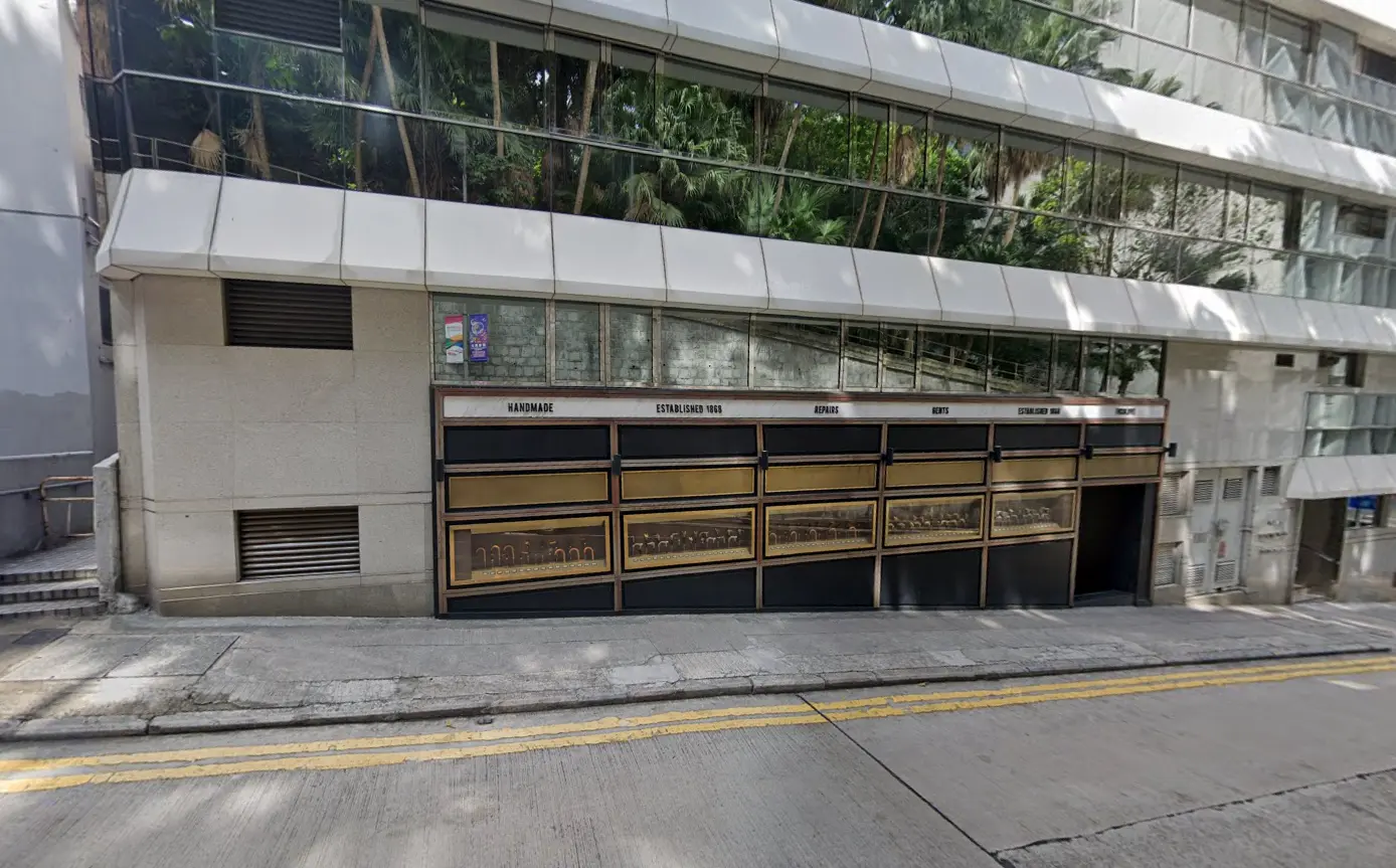 Glass office building with mirrored windows on Duddell Street in Central, brown garage doors, sloped street, yellow lines.