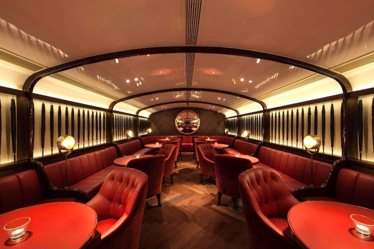 Lounge on Duddell Street in Central featuring red armchairs, round tables, soft lighting, and a mirrored wall.