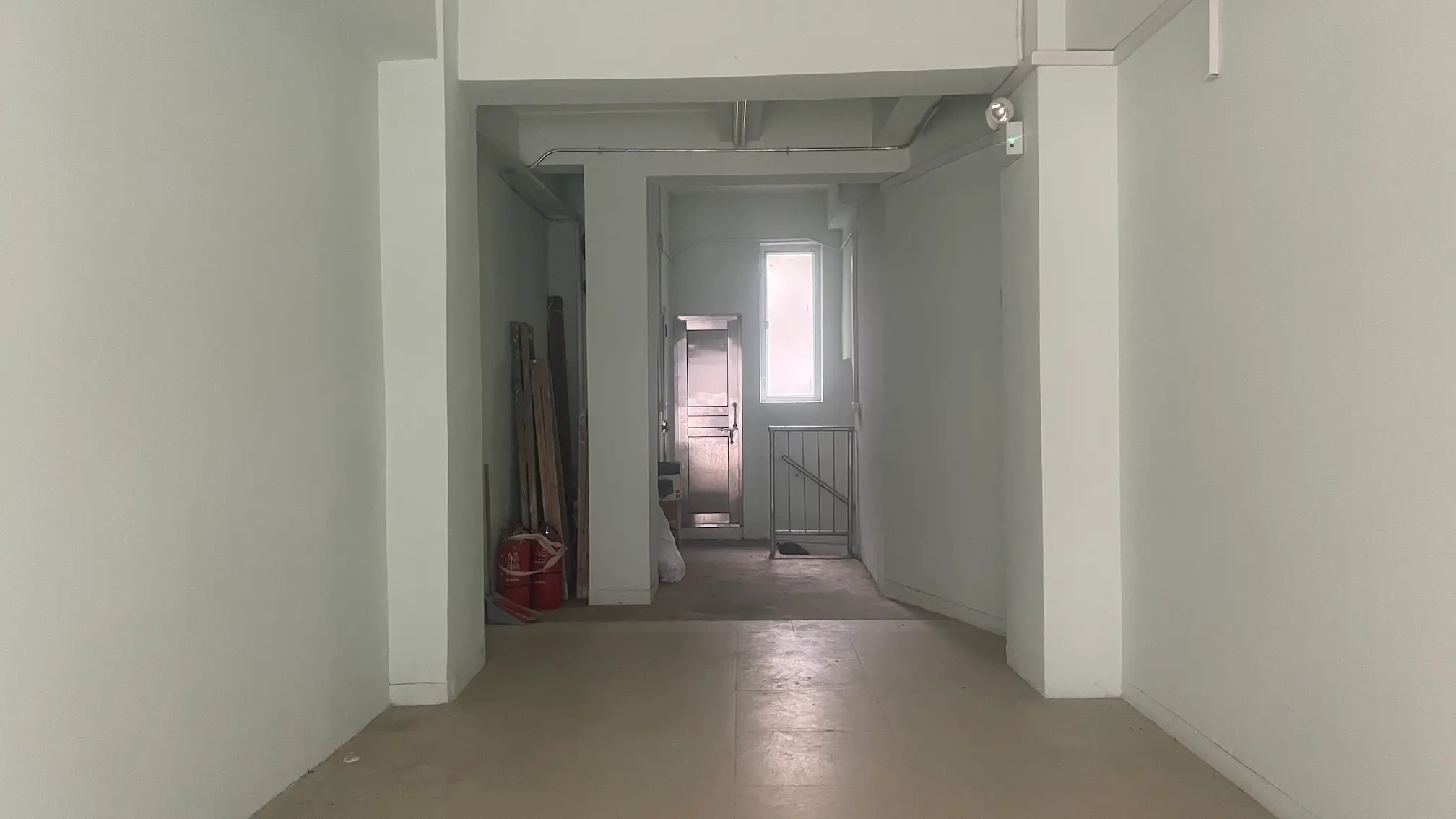 西營盤舖位。第一街一條狹窄走廊，設有淺色牆身、清潔工具，盡頭有一道門。