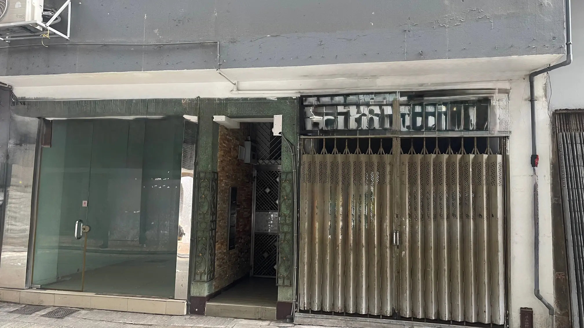 Shop on First Street, Sai Ying Pun. Storefront with glass windows, a metal gate, and worn exterior walls.