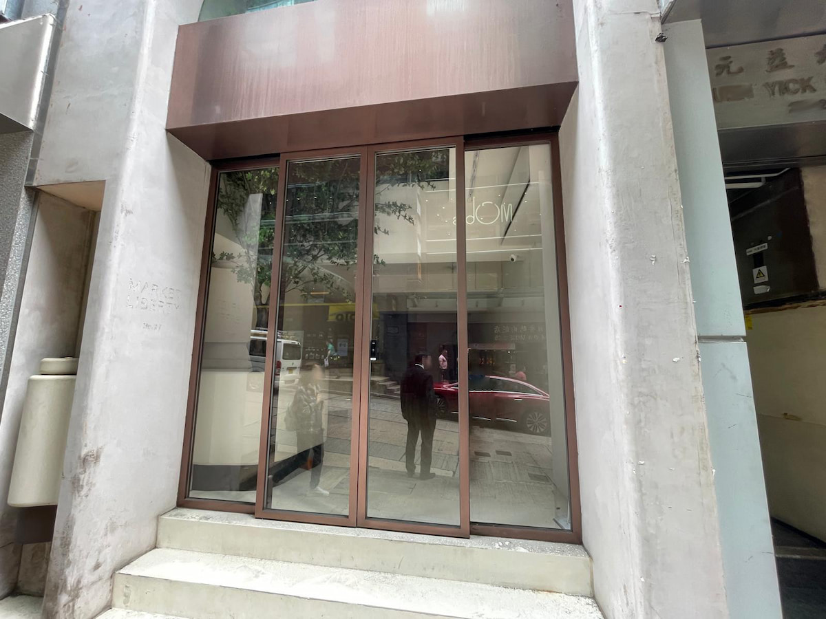 Glass storefront with brown framing on Wellington Street, reflecting city surroundings and people walking by in Central.