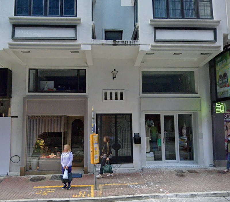 Shop on Lyndhurst Terrace, Central. Two people stand, outside a modern building with large windows and a black door.