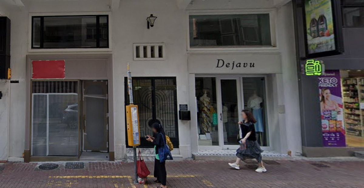 Two people walk past the white Dejavu storefront on Lyndhurst Terrace, Central, near a bus stop displaying mannequins.