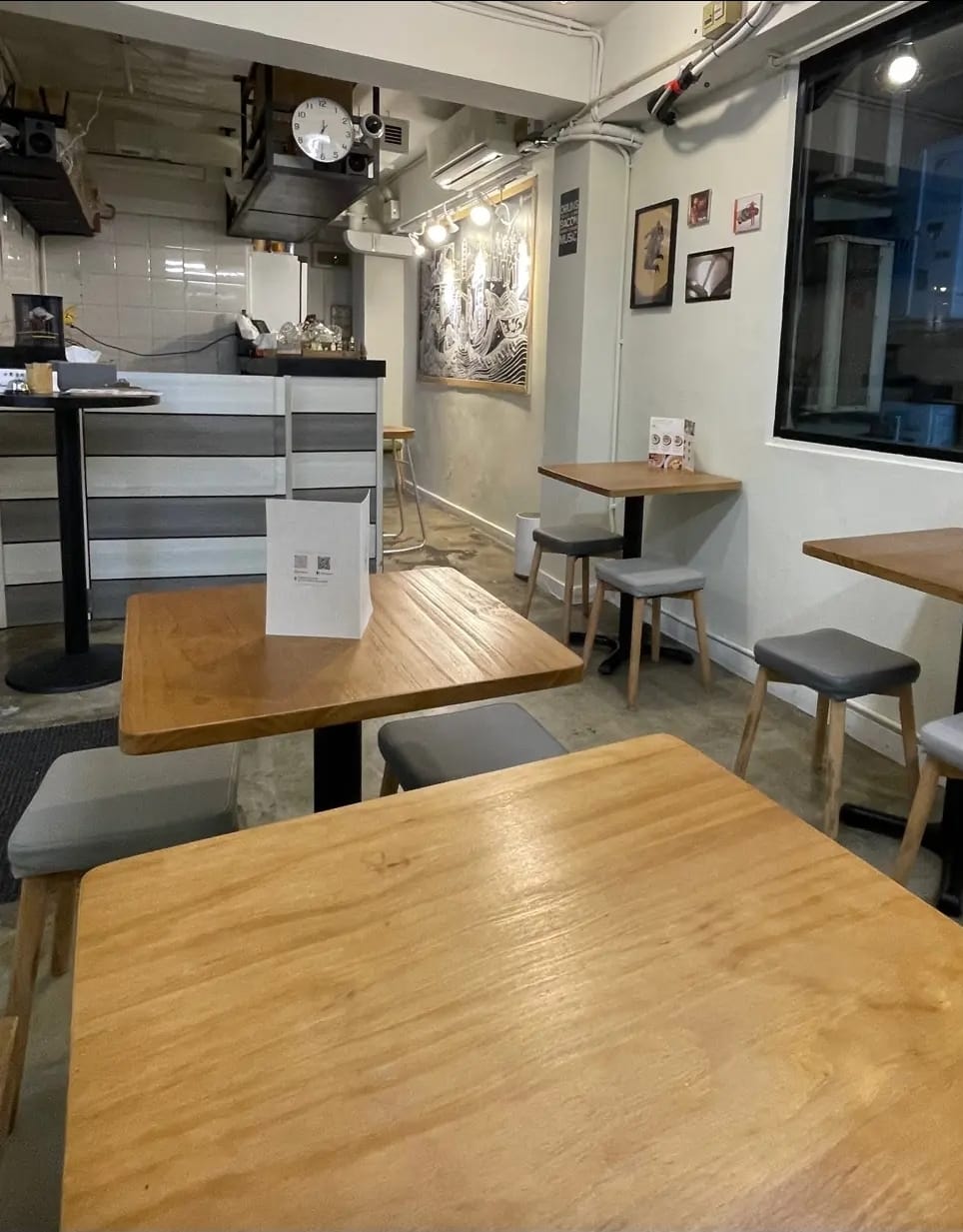 嘉咸街一間咖啡店內部，設有木餐枱、灰色座椅、牆上畫作及右邊窗戶。