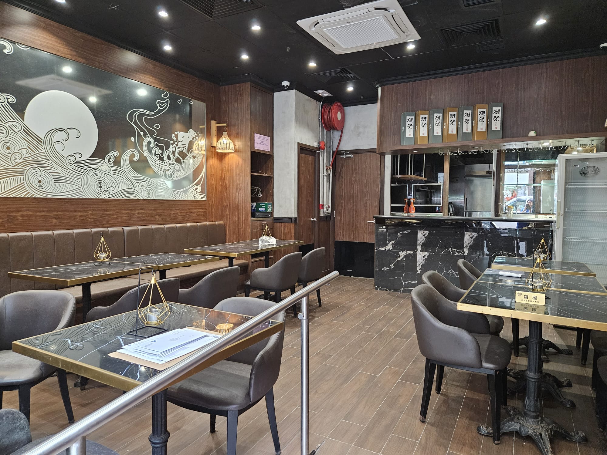 堅尼地城餐廳舖位。蝦莪街一間現代化餐廳內部,設有空置餐枱、啡色座椅、牆上畫作及上方餐牌板。