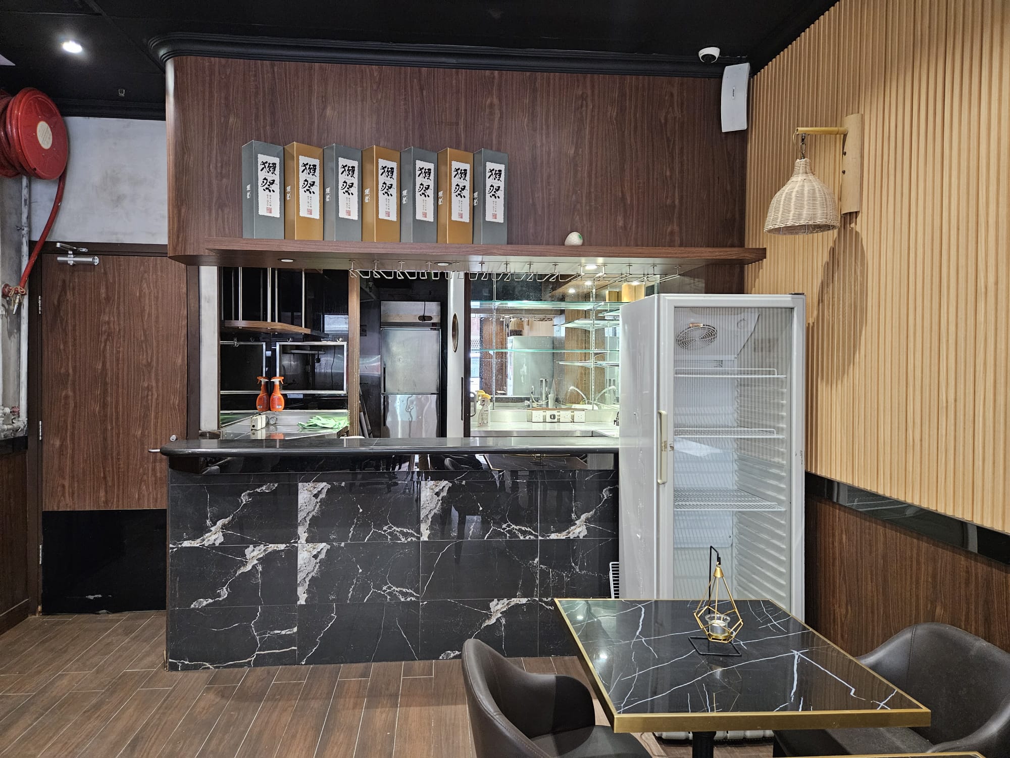 Kennedy Town restaurant counter with black marble, open shelves, and a table for two on Hau Wo Street.