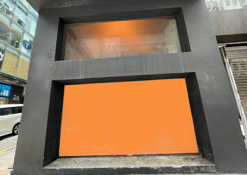 Shop on Wellington Street, Central. Black storefront with two rectangular windows, one featuring an opaque orange lower panel.