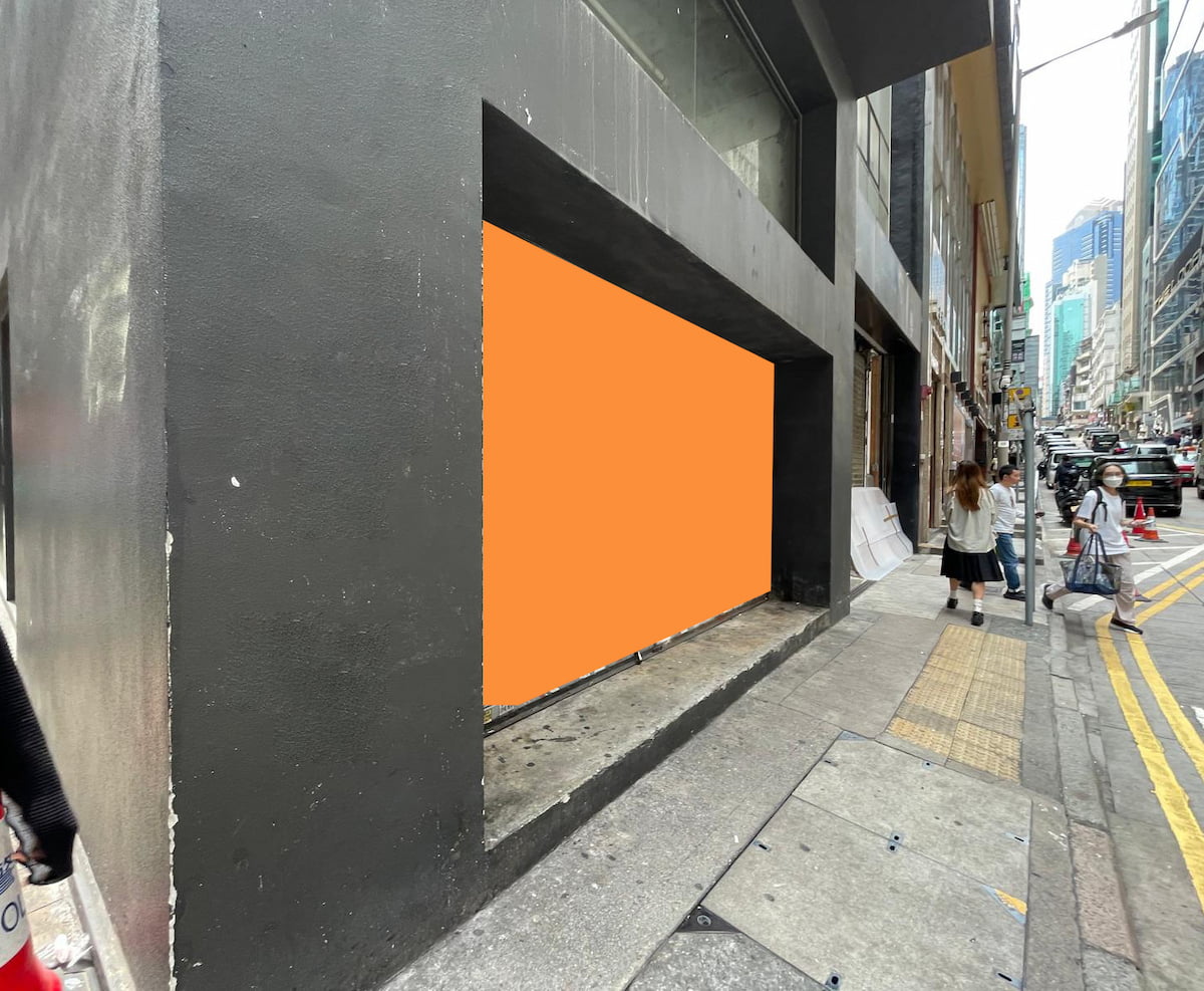 An orange rectangle covers a recessed window space on a gray building along Wellington Street’s sidewalk.