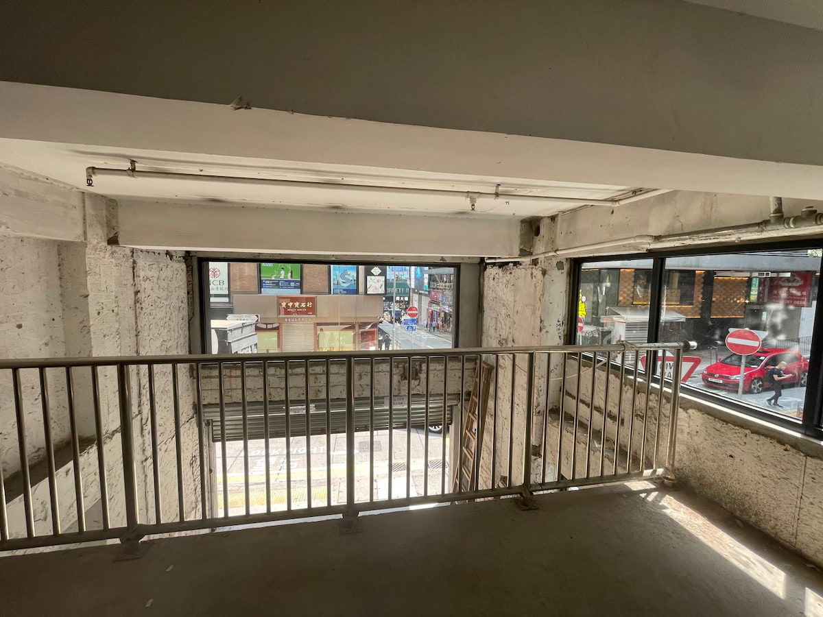 Unfinished room interior with metal railing, large windows, and view of Wellington Street in Central.
