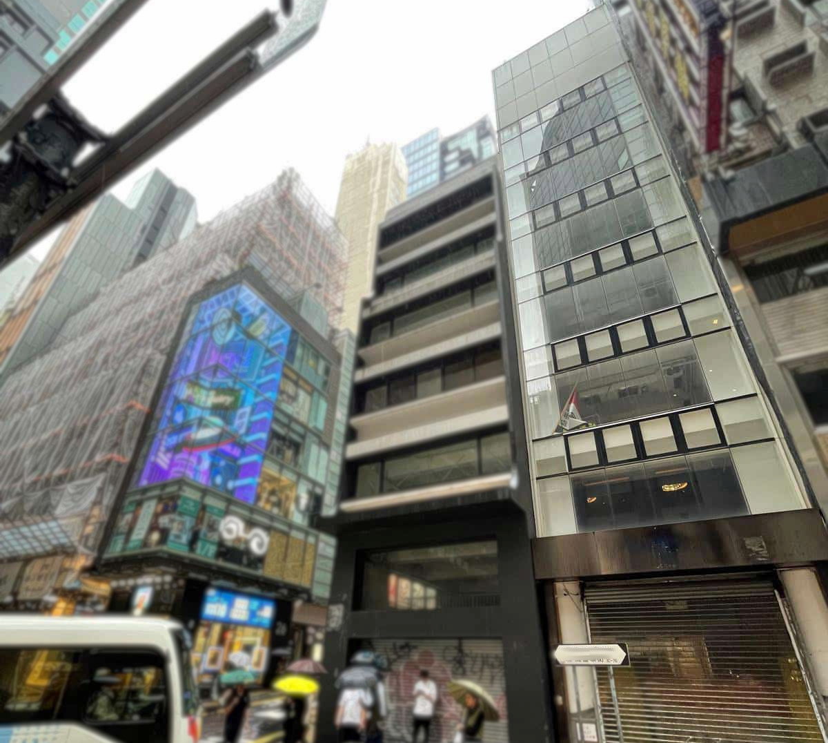 Tall narrow modern building with glass facade on Wellington Street Central, surrounded by older buildings and busy streets.