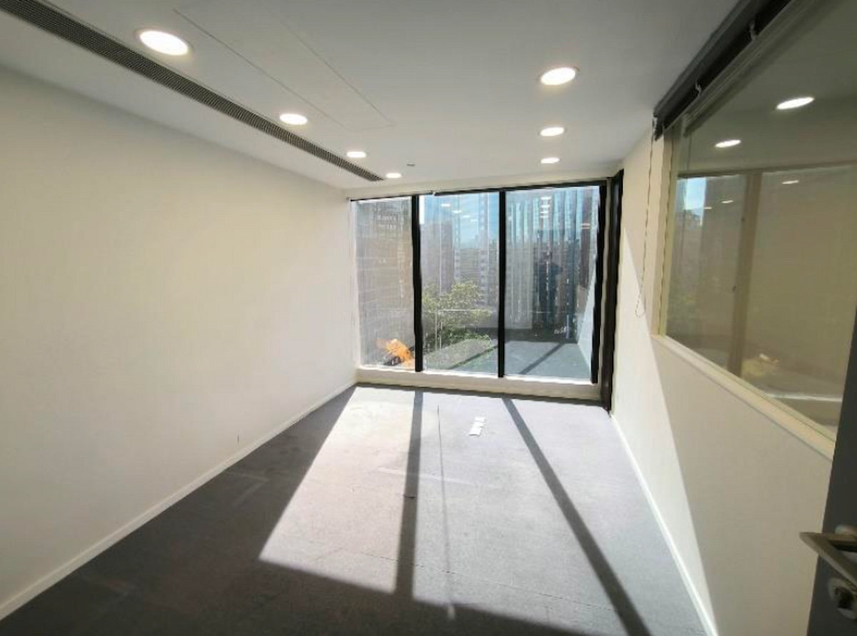 Empty office room with gray carpet, large windows on Granville Road in Tsim Sha Tsui, sunlight and city views visible.