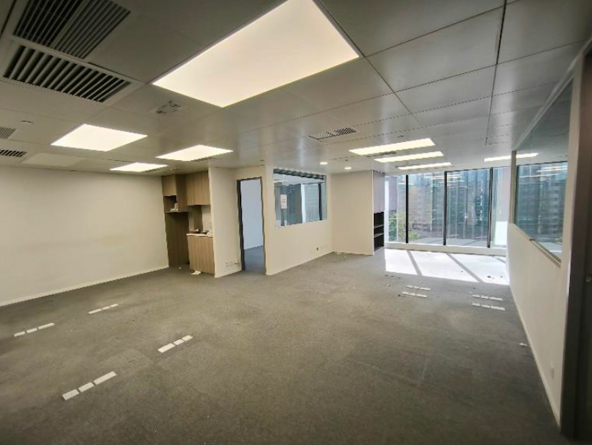 Unfurnished modern office on Granville Road, Tsim Sha Tsui, with gray carpet, built-in shelves and large side windows.