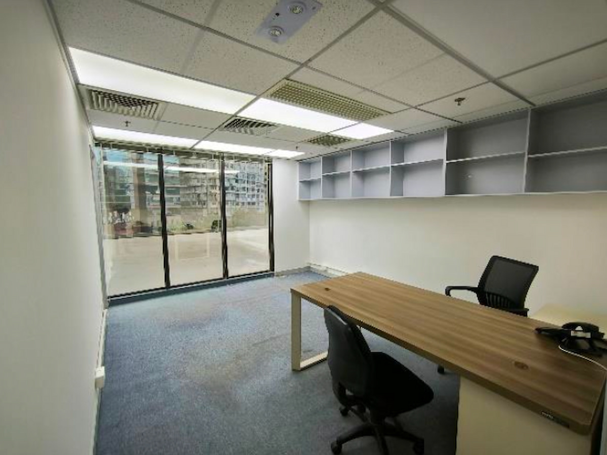 Office on Granville Road with a wooden desk, chairs, shelves, and large windows facing Tsim Sha Tsui.