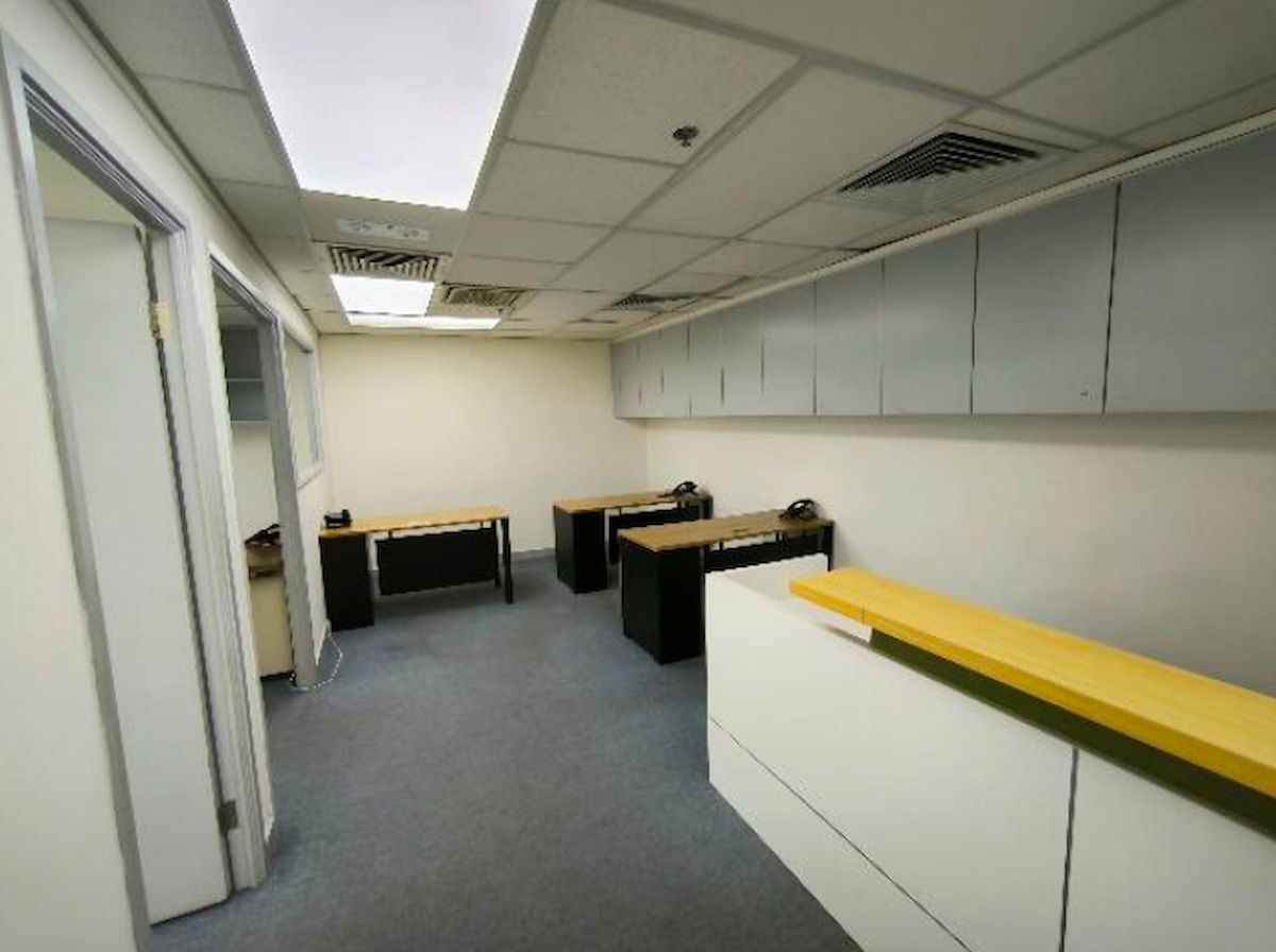 Small office on Granville Road, Tsim Sha Tsui with three desks, phones, cabinets, counter, grey carpet and white walls.