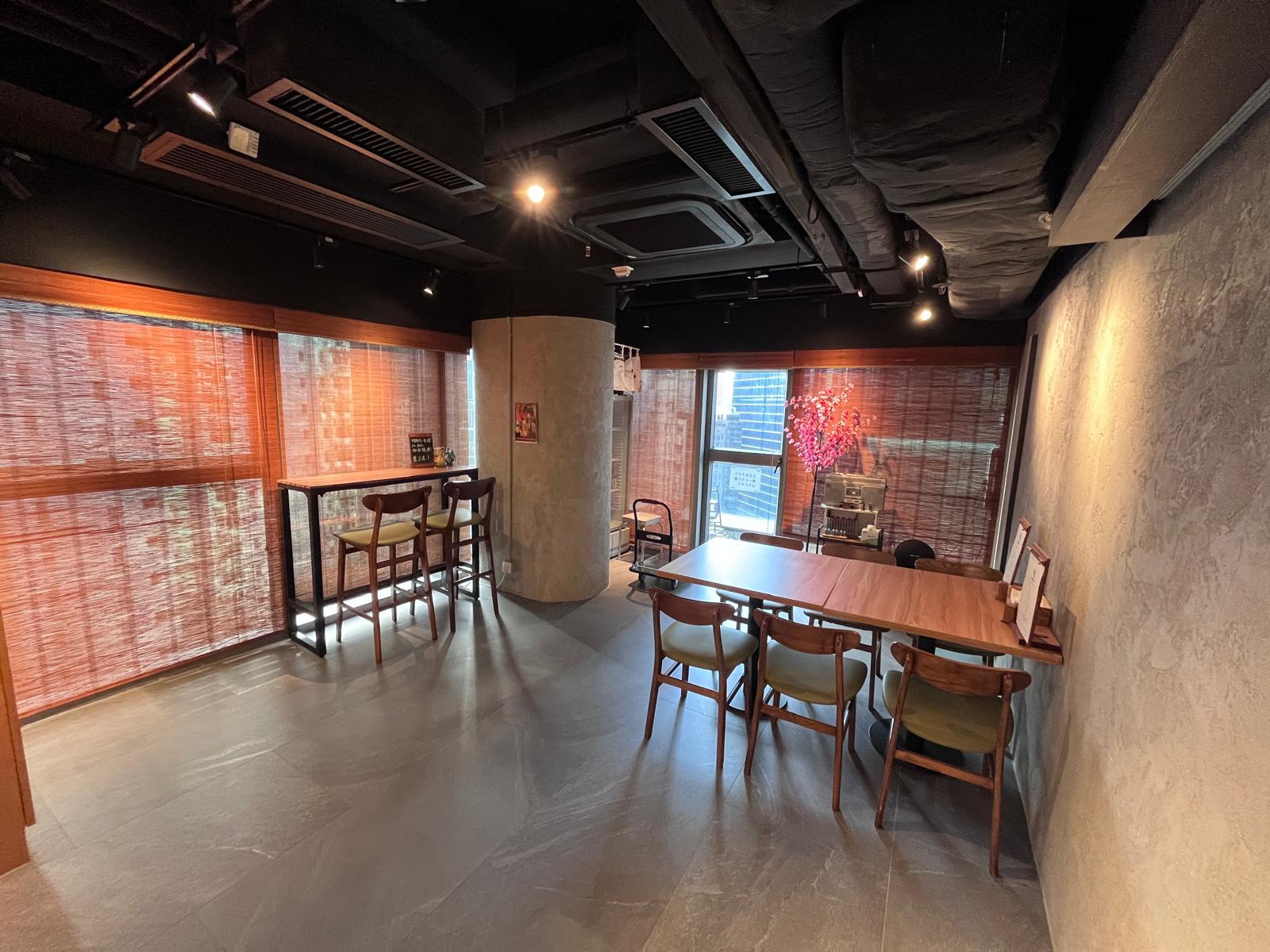 Modern room on Wellington Street Central with two tables, wooden chairs, large windows with blinds and window decorations.