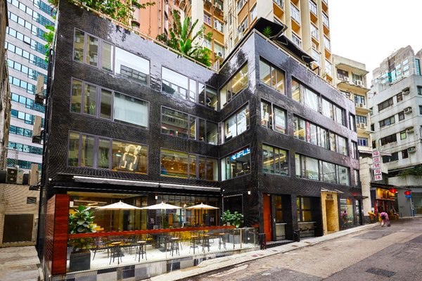 上環新街現代建築物鋪黑色磚牆,設大窗戶,地下咖啡店設戶外座位。