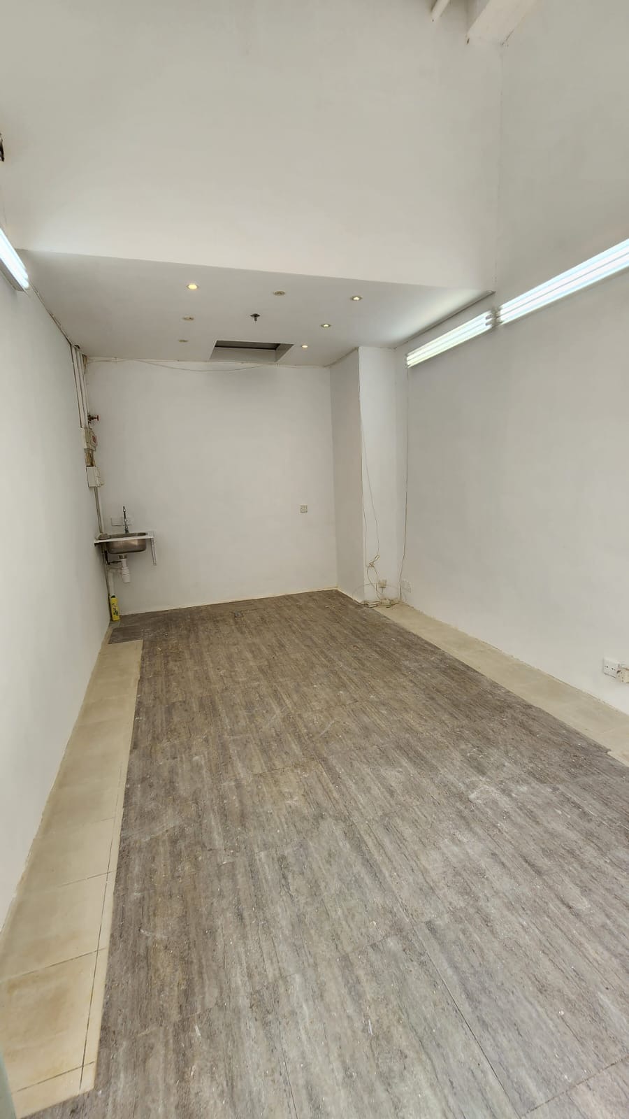 Empty room with white walls, tiled floor, and a small sink on Third Street in Sai Ying Pun.