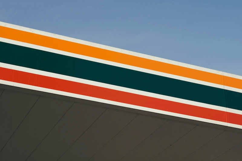 Gas station canopy with orange, green, and red stripes set against a clear blue sky.