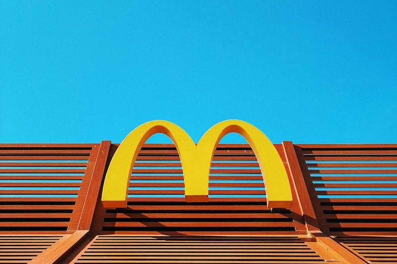 Yellow McDonald’s M logo on a brown slatted structure in Hong Kong with a blue sky above.
