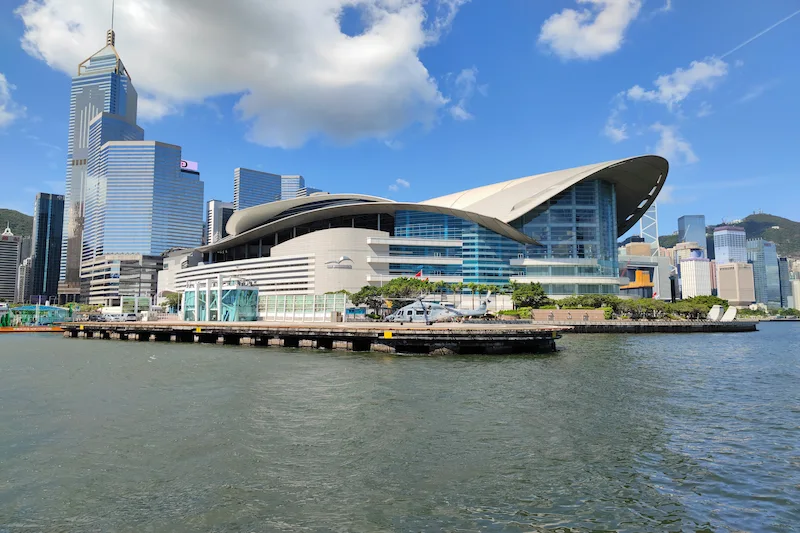 Modern convention center with a curved roof beside the water at Food Expo PRO under a clear blue sky.