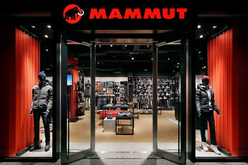 Mammut store entrance with two mannequins dressed in outdoor clothing and shelves of gear visible inside.