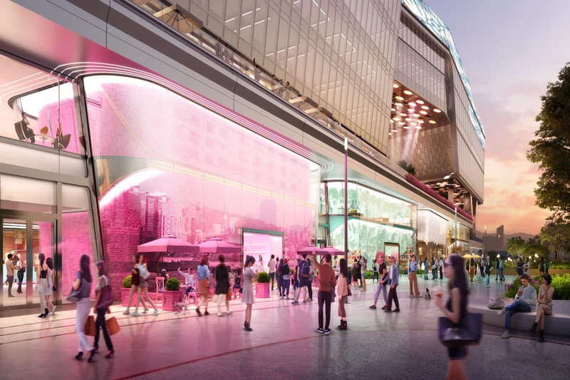 People walk past Central Yards, a modern building with pink-lit storefronts along the Hong Kong harbourfront.