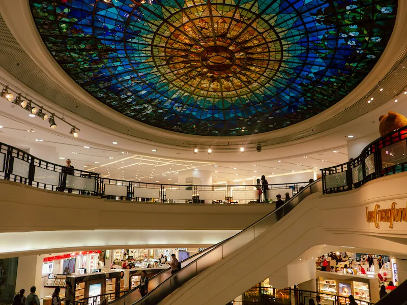 Shoppers walk through a mall space with a stained glass dome ceiling in Causeway Bay.