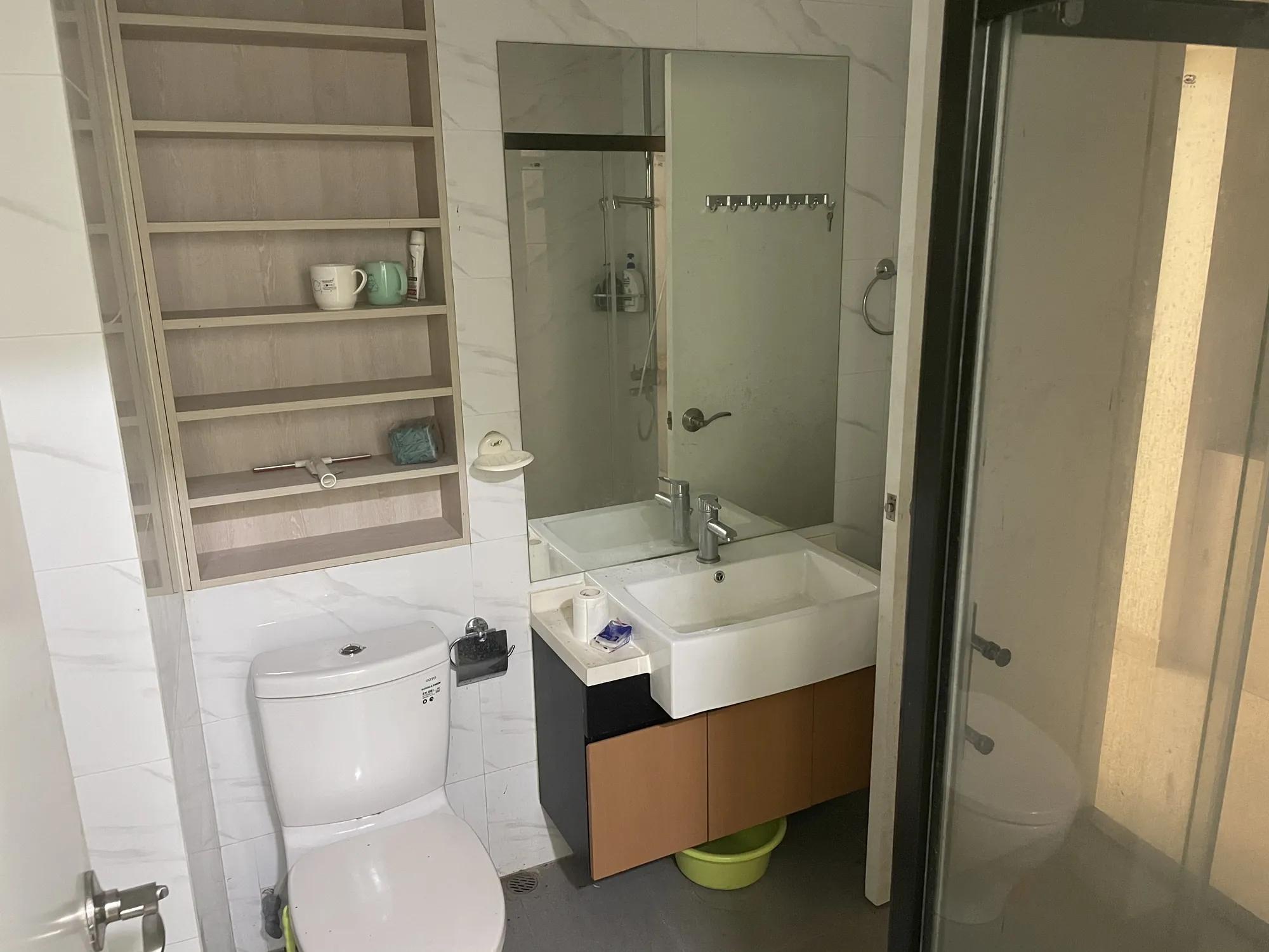 Bathroom on Central’s Hollywood Road with toilet, sink, mirror, glass shower and a green basin under the sink.