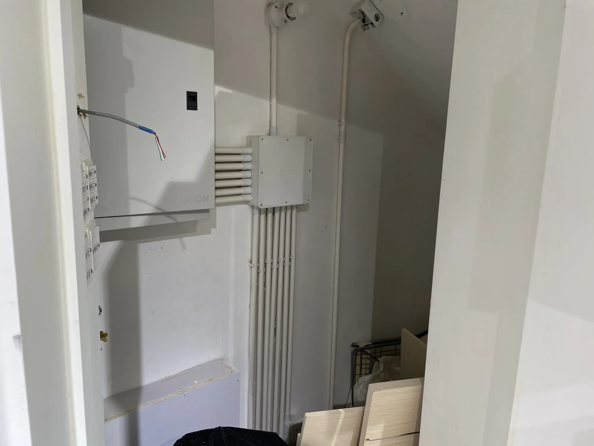 Utility closet on Hollywood Road in Central with exposed wiring, electrical panels, and conduit pipes.