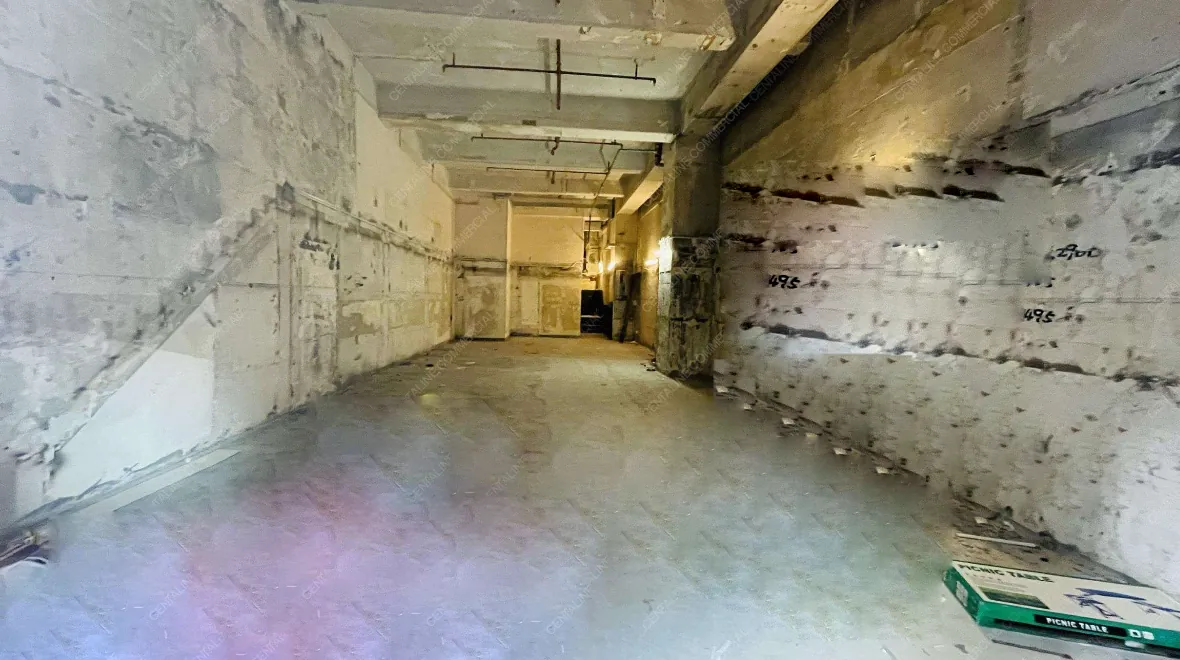 Ref#3315: Unfinished space ideal for a rental shop or office, with exposed ceiling pipes and wiring, marked walls, and a cardboard boxperfect for anyone seeking a customizable unit under renovation.