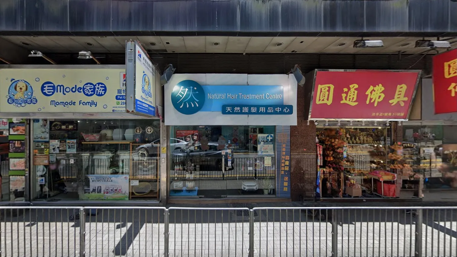 Street view on Java Road North Point with a pet store Natural Hair Treatment Center and Buddhist items shop.