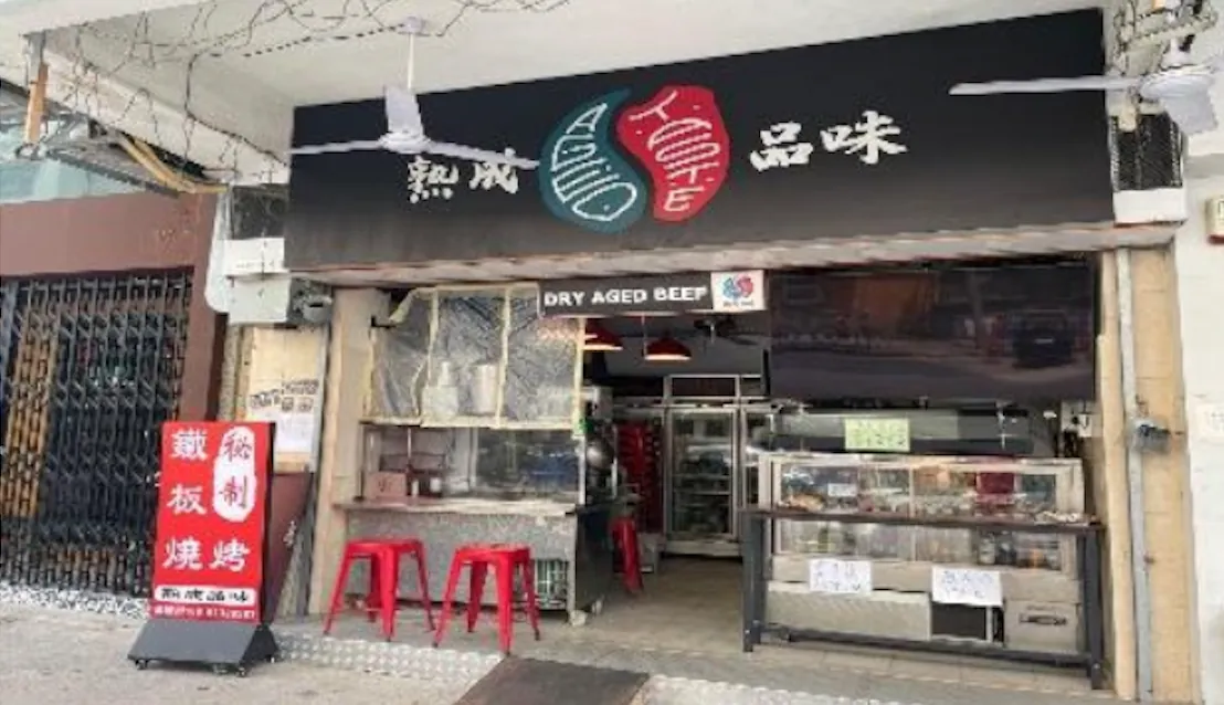 Street view of a restaurant on Ki Lung Street in Sham Shui Po with a black sign, red stools, and Dry Aged Beef label above.
