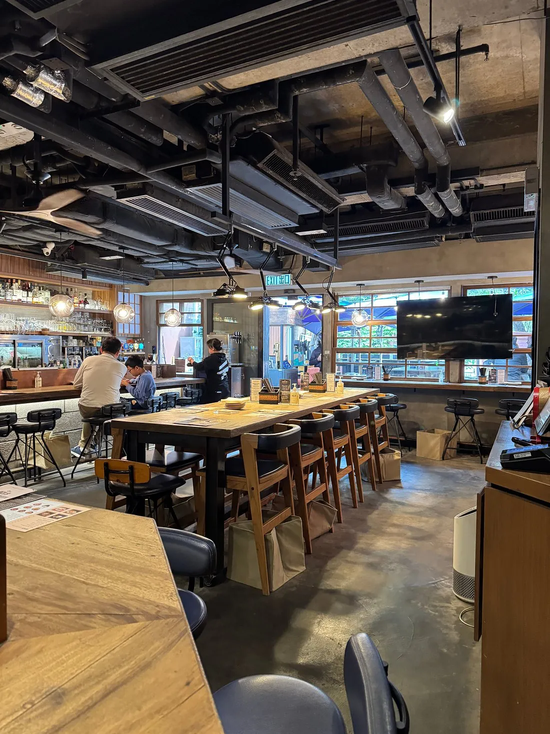 Modern restaurant interior on Pottinger Street, Central with wooden tables, exposed pipes, and diners inside.