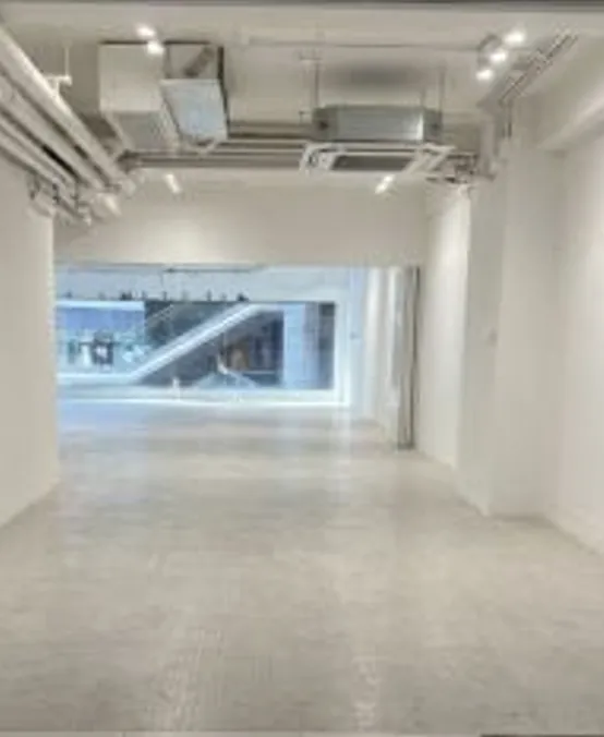 Shop on Queen's Road Central, Sheung Wan. White room with tiled floor, exposed ceiling pipes, large window, and view of escalator on Queen’s Road Central.