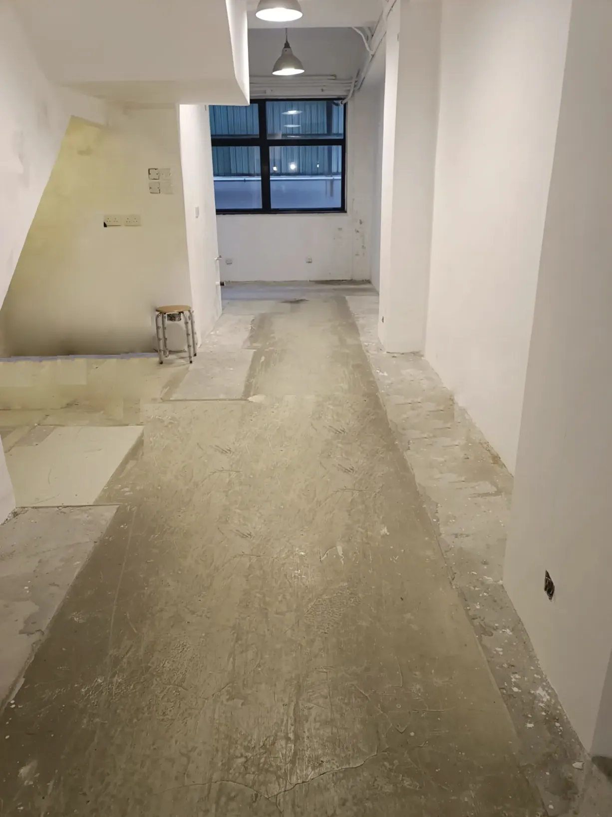 An empty hallway on Staunton Street with unfinished floors, white walls, and a window letting in natural light.
