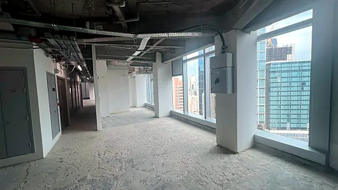 Restaurant space at H Code, Central – bare-shell corner with windows onto neighbouring towers