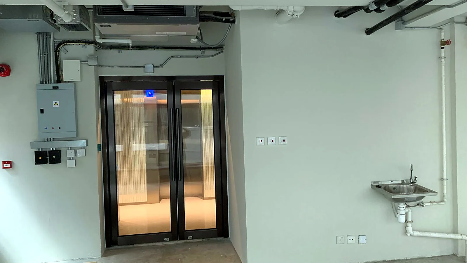 Unit entrance from the lift lobby with electrical board and pantry sink