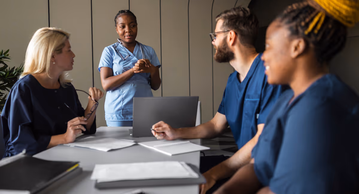 Diverse group of healthcare professionals in discussion during a clinical team meeting, highlighting collaboration and workforce planning in healthcare.