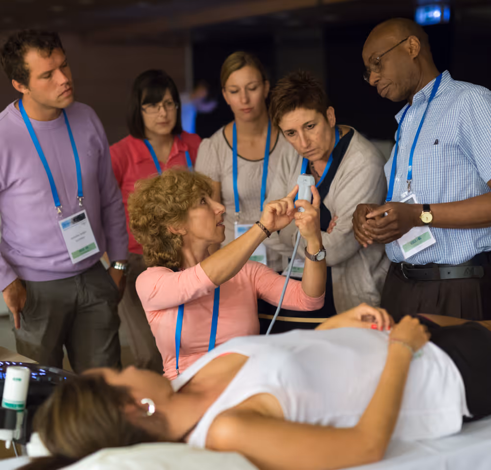 Group of healthcare professionals receiving hands-on ultrasound training during a live demonstration, guided by an experienced instructor at a clinical imaging workshop.