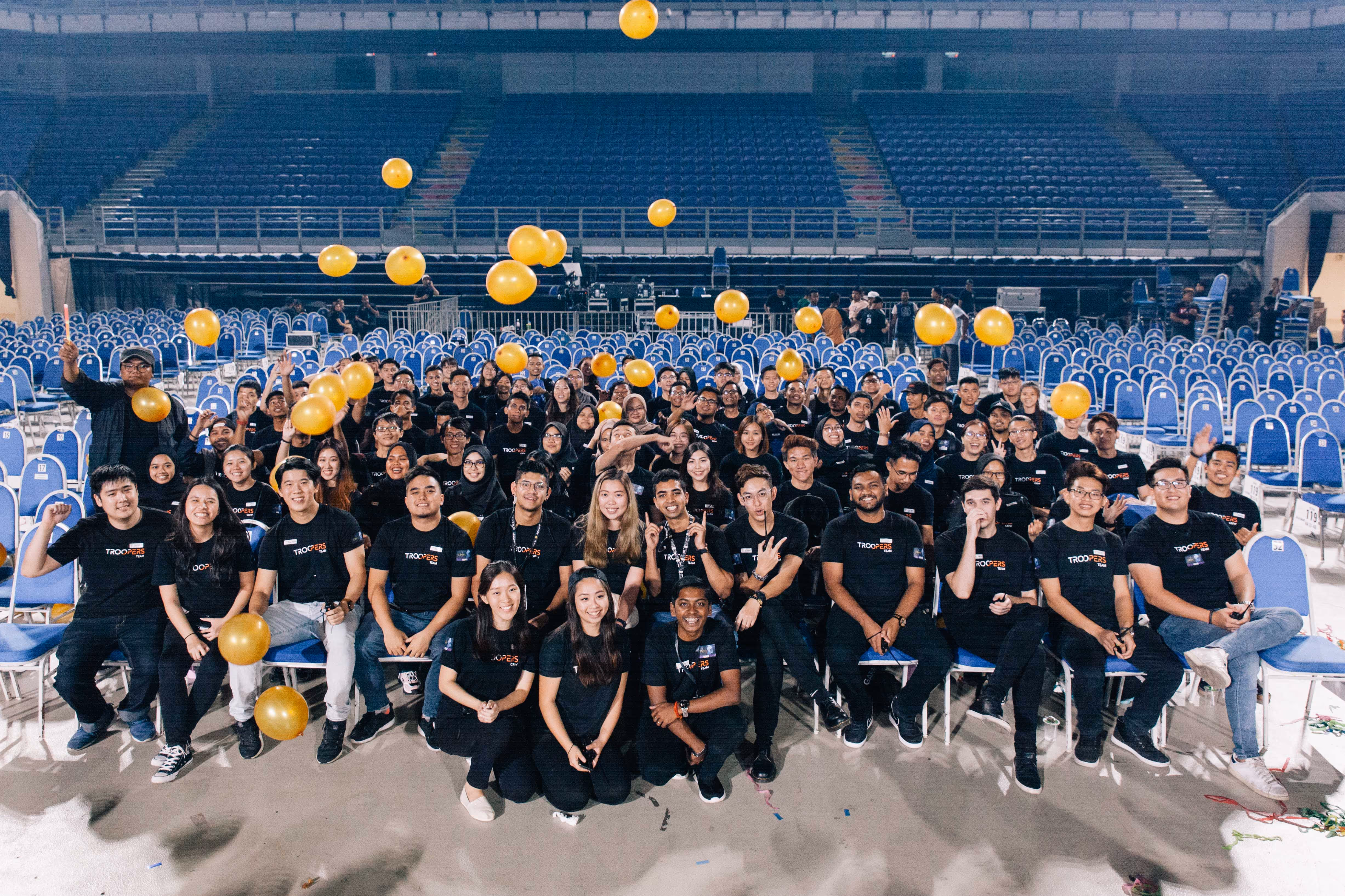TROOPERS team celebrating a successful event, showcasing diversity and inclusion at a large indoor venue.