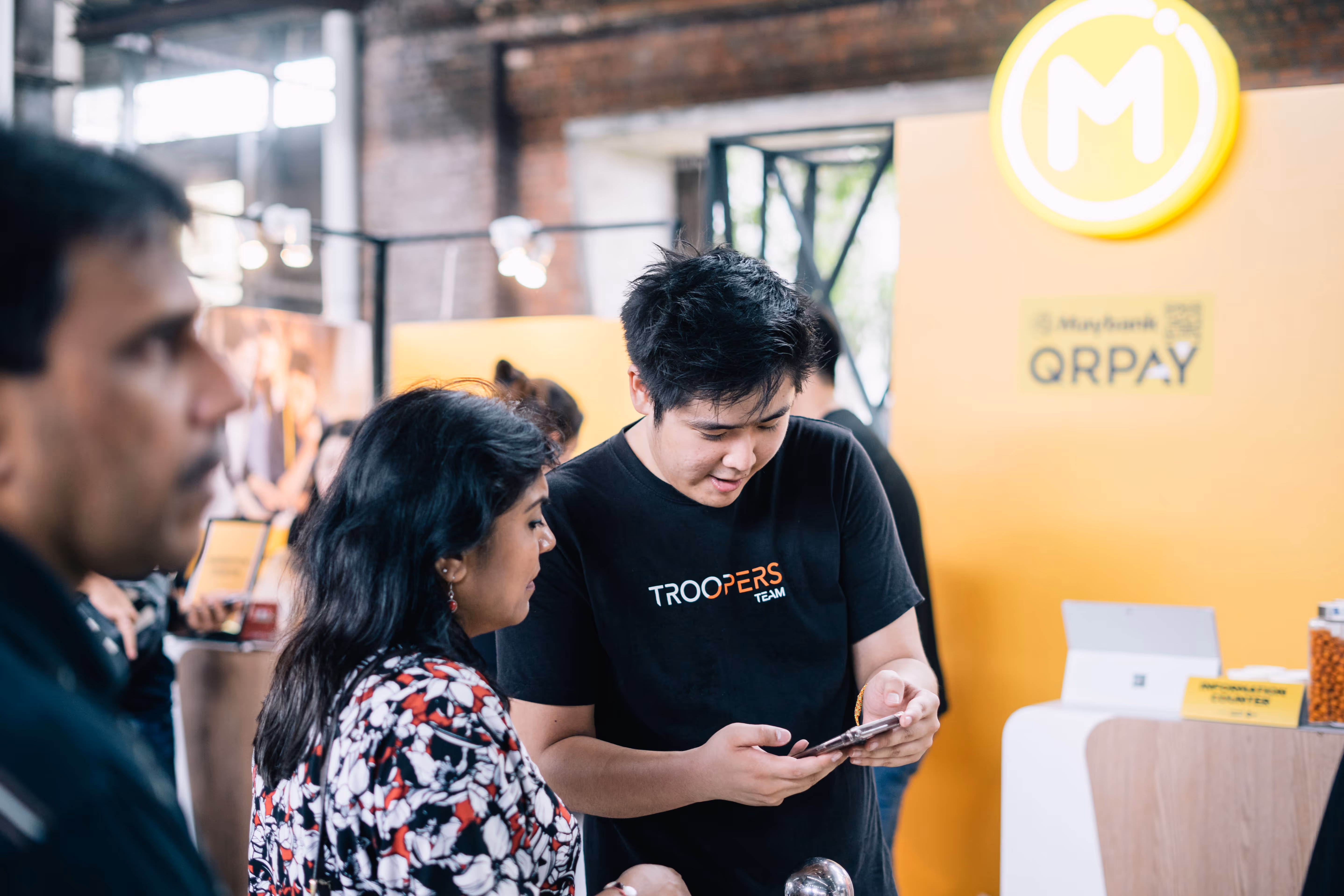 TROOPERS team member assisting a potential gig worker with the TROOPERS app at an event booth.