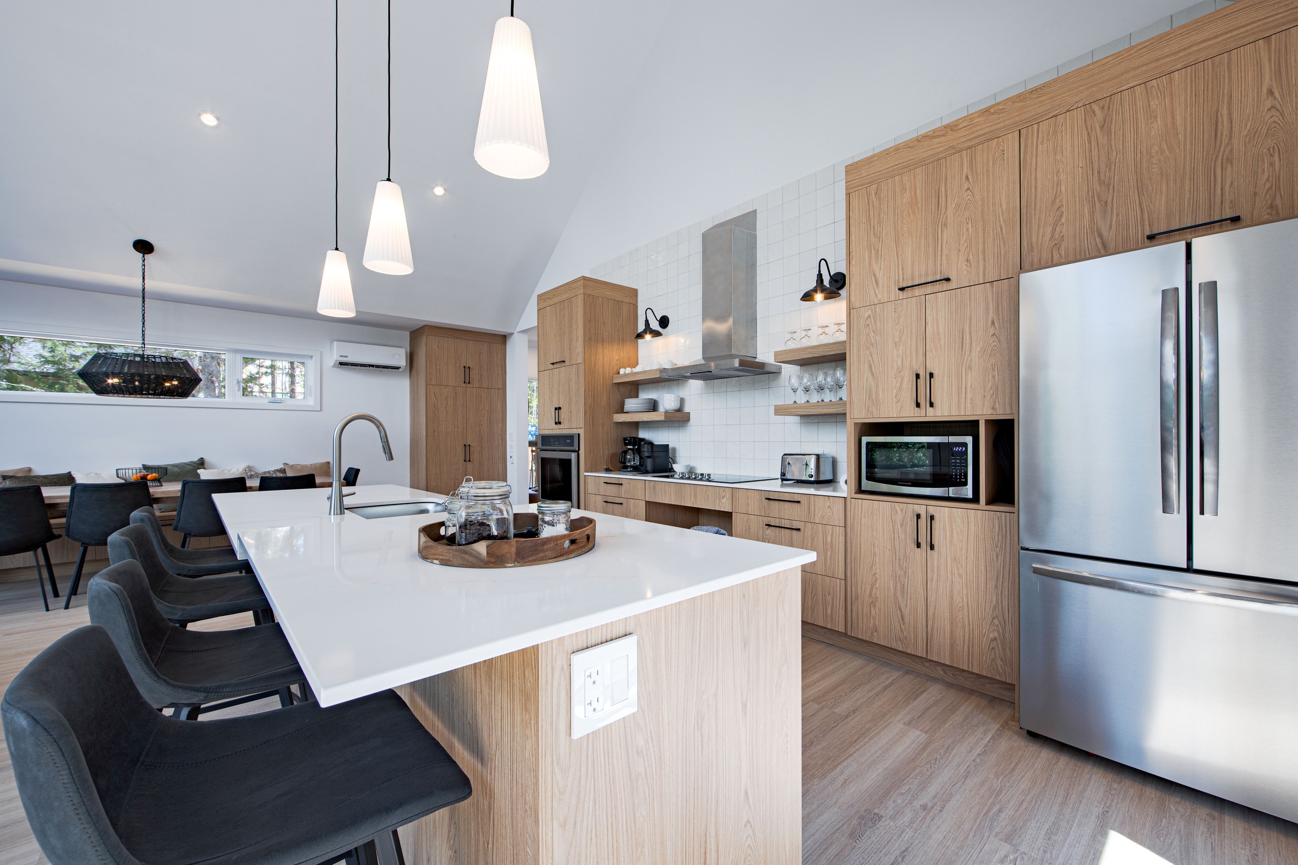 Chalet Le Boréal cuisine îlot de quartz blanc armoires de bois clair plafond cathédral et électroménagers en acier inoxydable