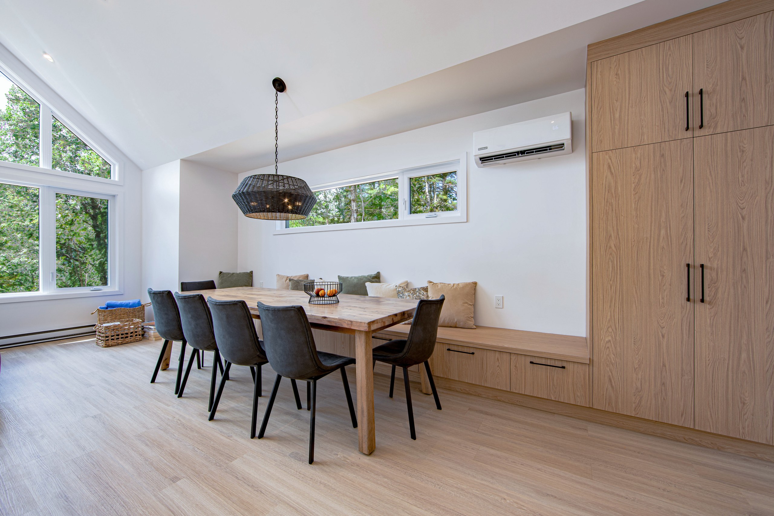 Chalet Le Boréal salle à manger longue table de bois banquette intégrée et grandes fenêtres sur la forêt