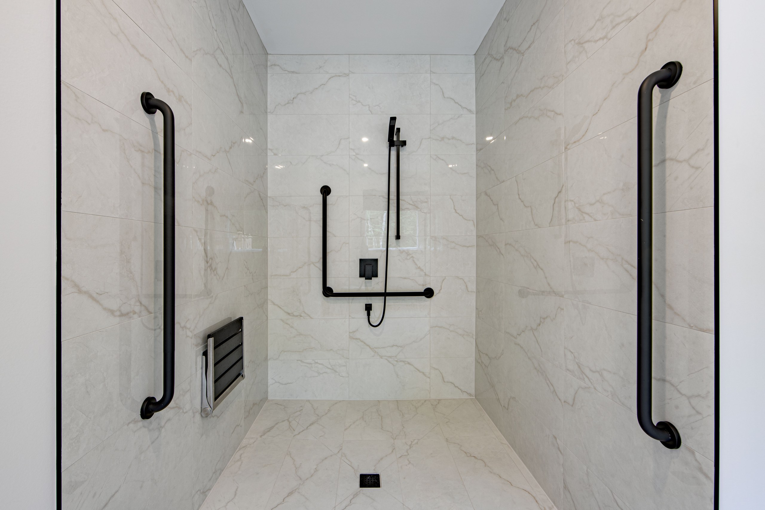 Chalet Le Boréal douche adaptée sans seuil barres d’appui noires douchette à main et carrelage marbré